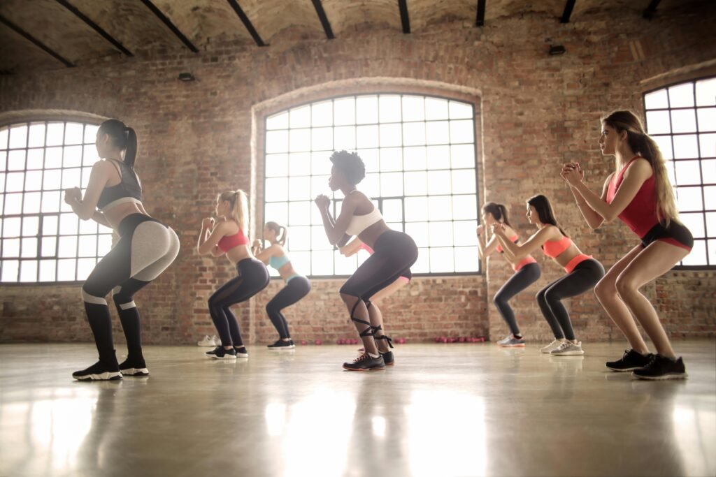 varias mulheres fazendo um exemplo de exercício agachamento
